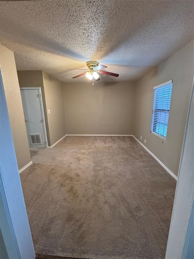 spare room featuring ceiling fan, carpet, and a textured ceiling