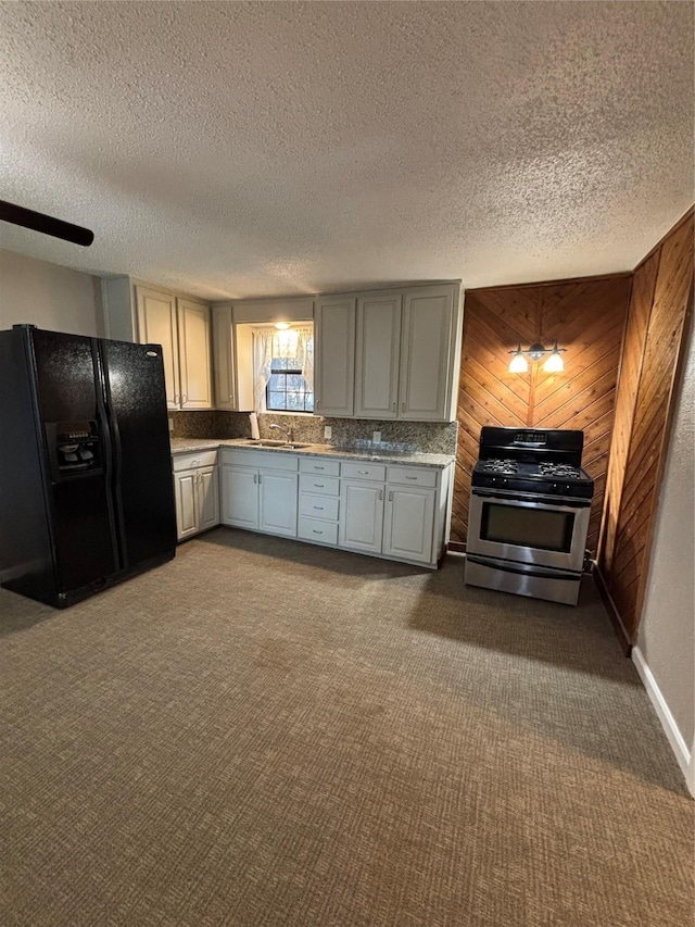 kitchen with gas stove, wooden walls, gray cabinetry, and black fridge with ice dispenser