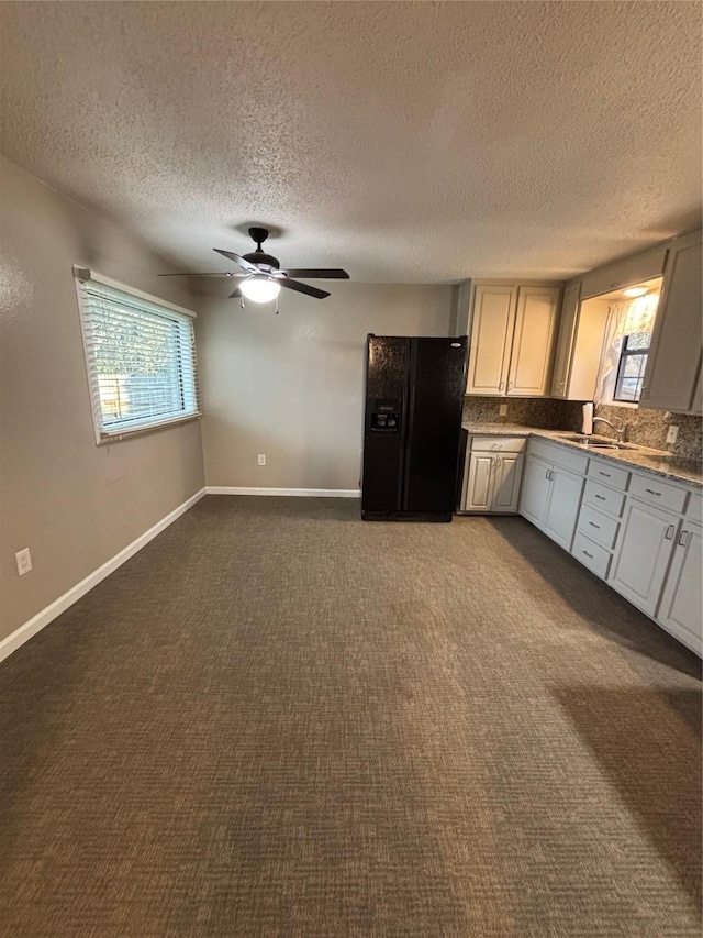 kitchen featuring dark colored carpet, black fridge, and a healthy amount of sunlight