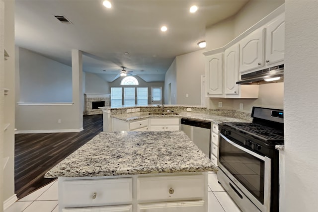 kitchen featuring a stone fireplace, sink, white cabinets, kitchen peninsula, and stainless steel appliances