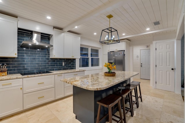 kitchen featuring white cabinetry, stainless steel fridge, a center island, black electric cooktop, and wall chimney exhaust hood