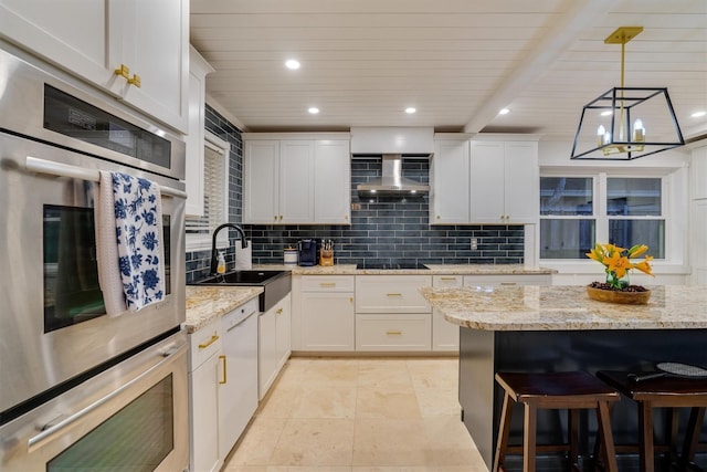 kitchen featuring pendant lighting, sink, wall chimney range hood, and white cabinets