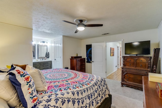 bedroom featuring ceiling fan, a textured ceiling, and ensuite bathroom