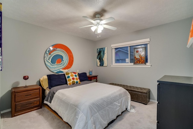 bedroom with light carpet, ceiling fan, and a textured ceiling