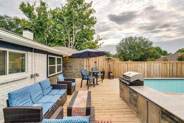 wooden deck with an outdoor kitchen, area for grilling, an outdoor hangout area, and a fenced in pool