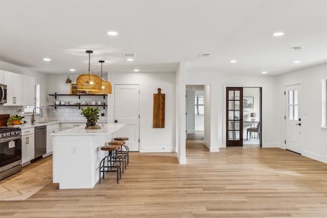 kitchen featuring a kitchen bar, sink, a kitchen island, stainless steel appliances, and white cabinets