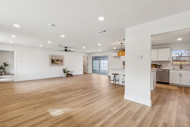 unfurnished living room featuring sink, ceiling fan, and light wood-type flooring