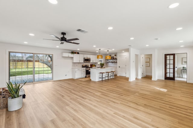 unfurnished living room with ceiling fan and light hardwood / wood-style floors