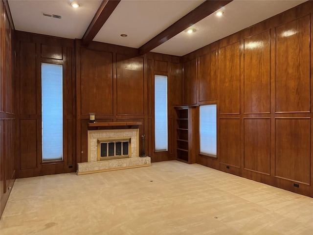 unfurnished living room with wooden walls, a premium fireplace, and beam ceiling