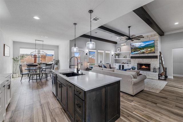 kitchen with pendant lighting, white cabinetry, sink, a kitchen island with sink, and light hardwood / wood-style flooring