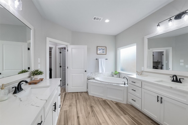 bathroom with vanity, hardwood / wood-style floors, and a washtub