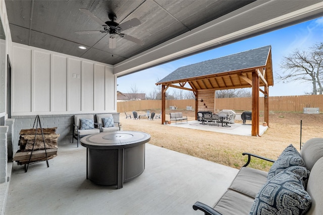 view of patio with a gazebo, ceiling fan, and an outdoor living space with a fire pit