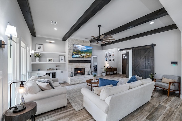 living room featuring ceiling fan, a barn door, beam ceiling, and light hardwood / wood-style flooring