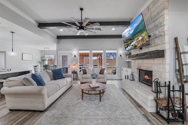 living room with beamed ceiling, ceiling fan, a fireplace, and hardwood / wood-style floors