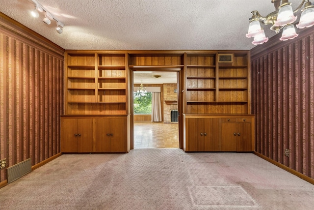 empty room with an inviting chandelier, light colored carpet, and a textured ceiling