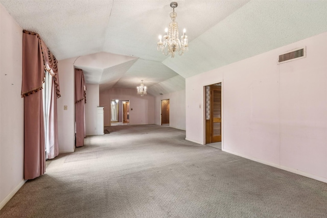 carpeted spare room featuring vaulted ceiling, a textured ceiling, and a chandelier