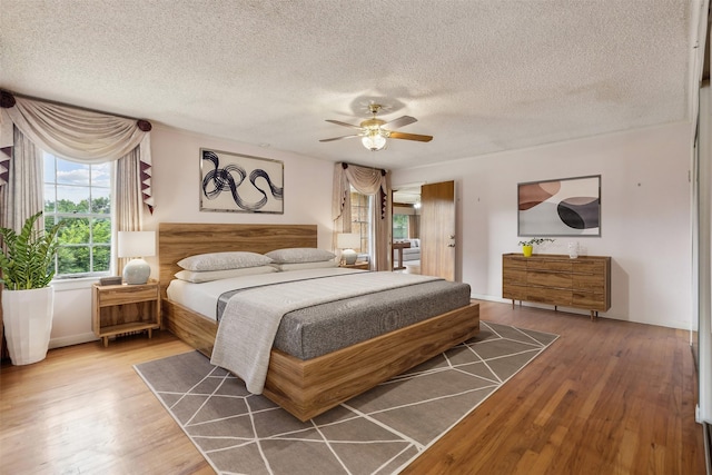 bedroom with hardwood / wood-style flooring, ceiling fan, and a textured ceiling