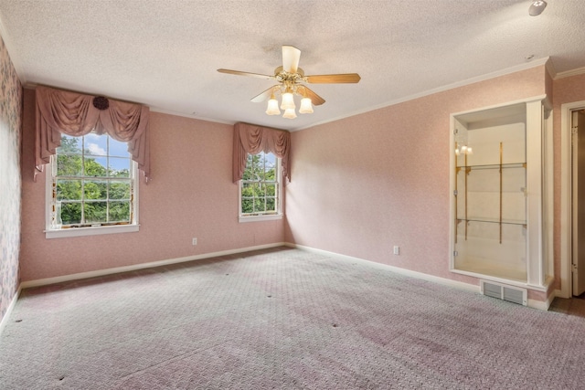 carpeted spare room featuring crown molding, ceiling fan, and a textured ceiling