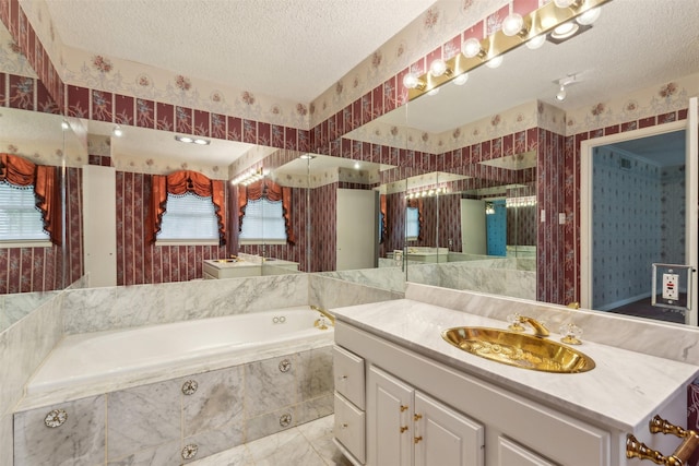 bathroom with vanity, a relaxing tiled tub, and a textured ceiling