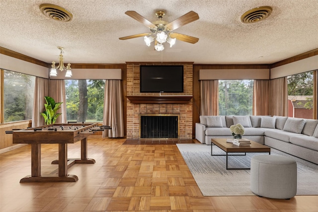 living room featuring a textured ceiling, a fireplace, light parquet flooring, and ceiling fan with notable chandelier