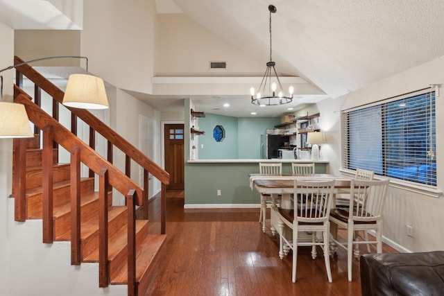 dining area featuring lofted ceiling, dark wood-type flooring, a textured ceiling, and an inviting chandelier