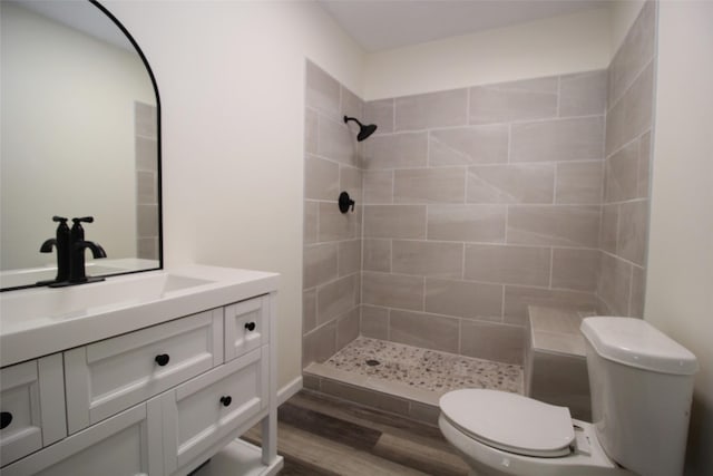 231 N 5th Ave, Munday, TX 76371 - bathroom featuring hardwood / wood-style floors, vanity, a tile shower, and toilet