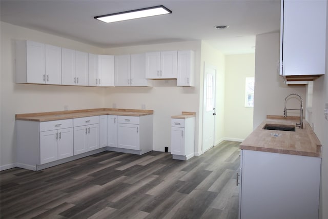 231 N 5th Ave, Munday, TX 76371 - kitchen featuring white cabinetry, sink, dark hardwood / wood-style floors, and wooden counters