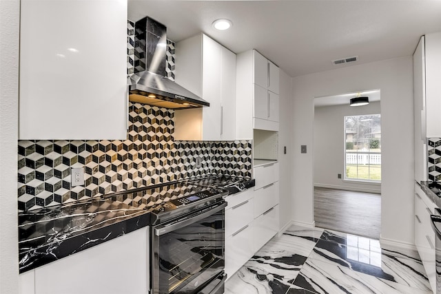 kitchen featuring wall chimney range hood, electric range, tasteful backsplash, white cabinets, and dark stone counters