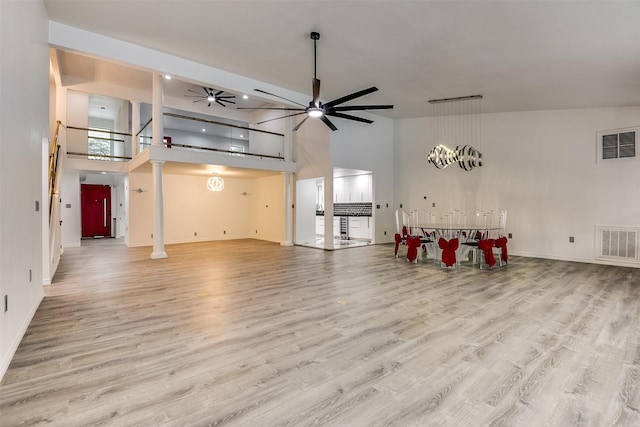 living room featuring ceiling fan, a high ceiling, light hardwood / wood-style flooring, and ornate columns