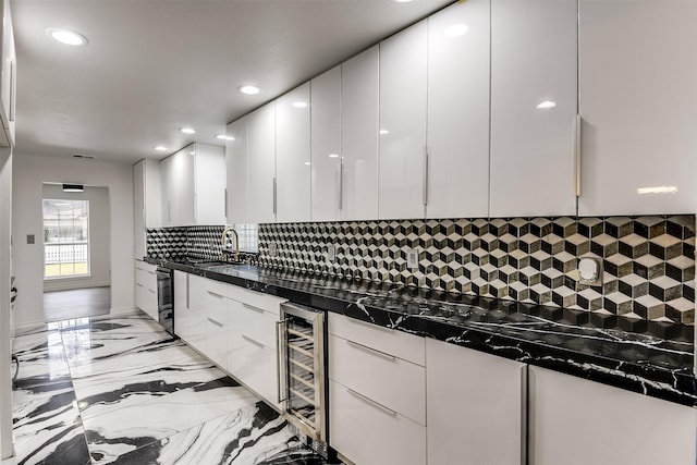 kitchen featuring dark stone countertops, backsplash, beverage cooler, and white cabinets