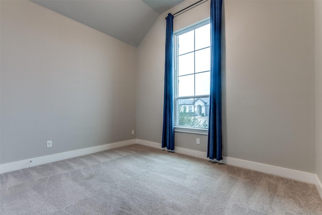 carpeted empty room with vaulted ceiling