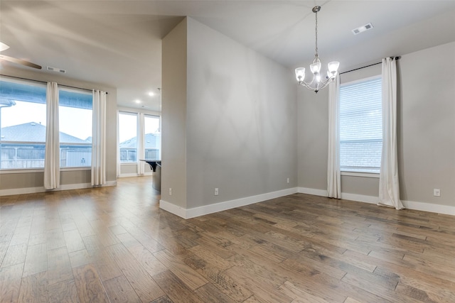 empty room with an inviting chandelier and wood-type flooring