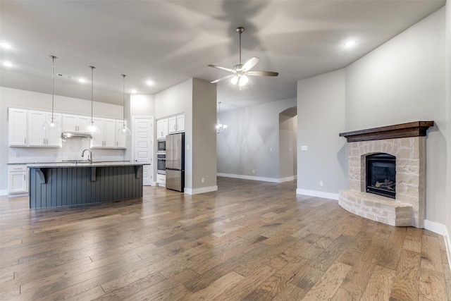 unfurnished living room featuring sink, a fireplace, dark hardwood / wood-style floors, and ceiling fan