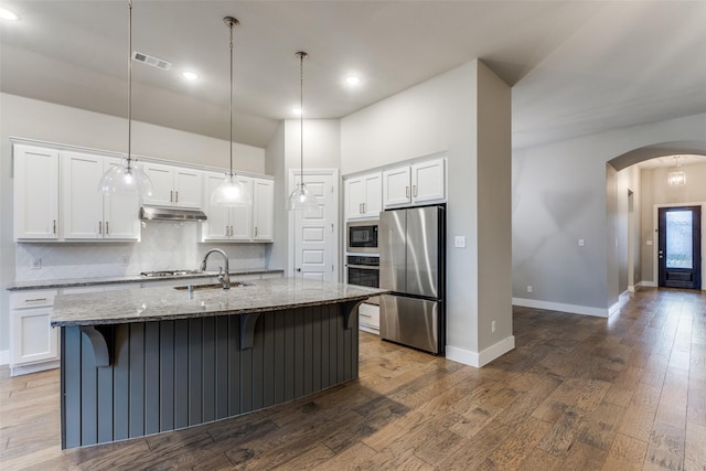 kitchen with white cabinetry, a kitchen island with sink, stone counters, and appliances with stainless steel finishes