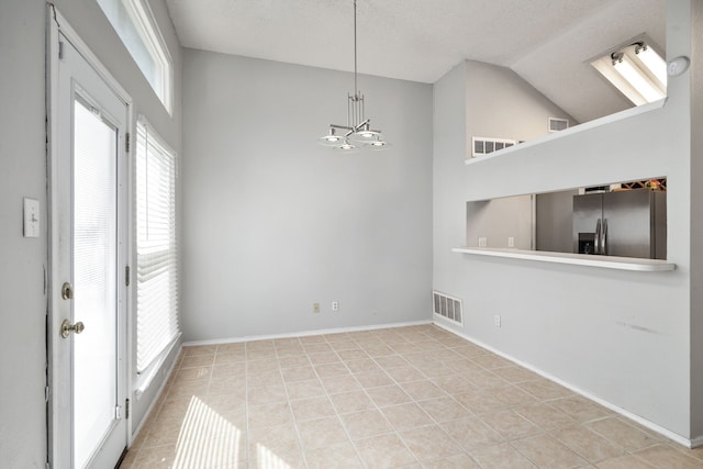 unfurnished room featuring light tile patterned flooring, lofted ceiling, a notable chandelier, and a textured ceiling