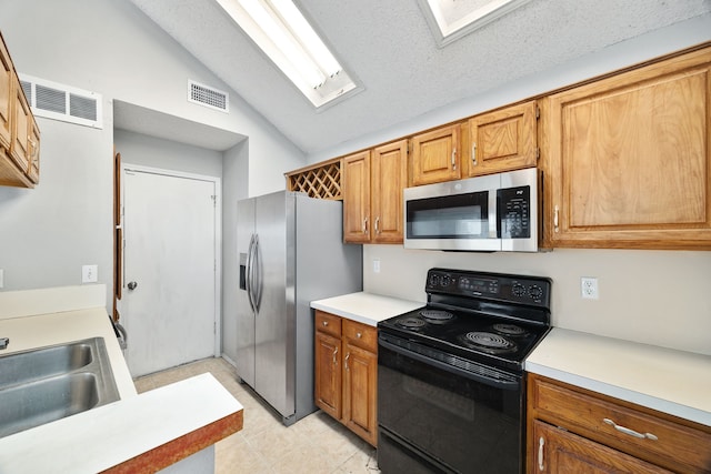 kitchen with sink, lofted ceiling with skylight, a textured ceiling, and appliances with stainless steel finishes