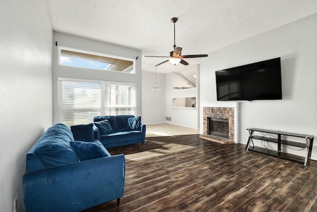 living room with a brick fireplace, hardwood / wood-style floors, a textured ceiling, and ceiling fan