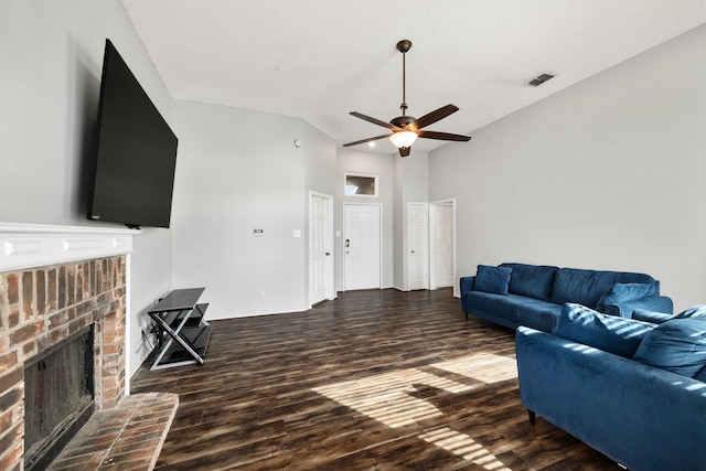 living room with vaulted ceiling, a brick fireplace, a textured ceiling, dark hardwood / wood-style floors, and ceiling fan