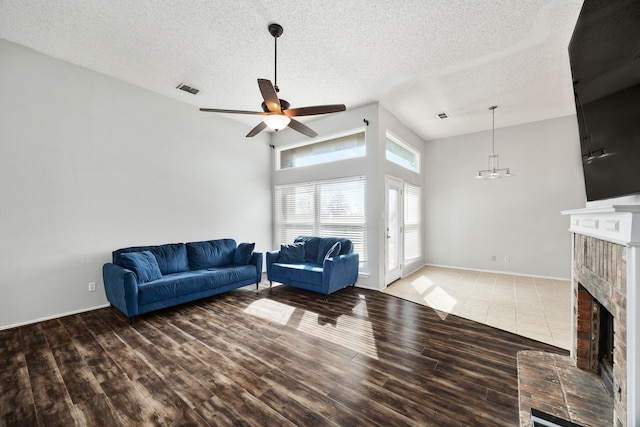 living room featuring a brick fireplace, hardwood / wood-style floors, a textured ceiling, and ceiling fan