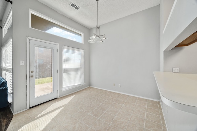 dining space featuring a chandelier, a textured ceiling, and light tile patterned floors