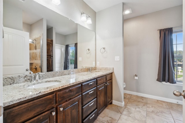 bathroom featuring tiled shower, vanity, toilet, and a wealth of natural light