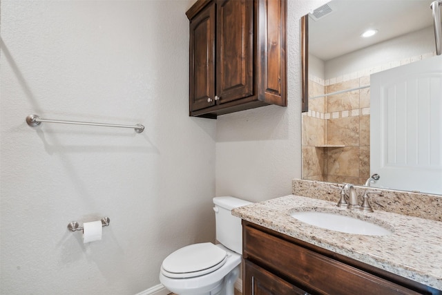 bathroom with walk in shower, vanity, and toilet