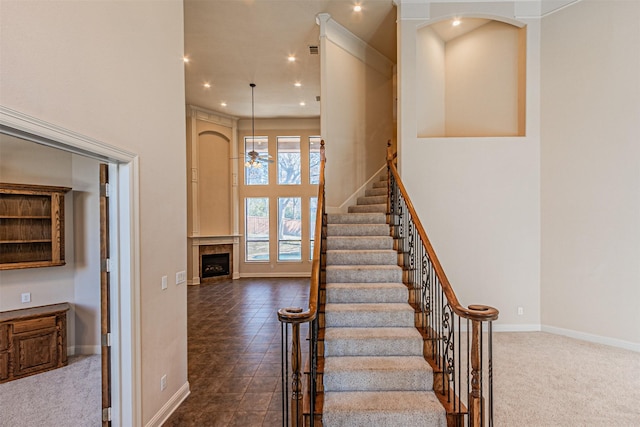 stairway featuring a high ceiling, carpet floors, and ceiling fan