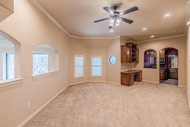 unfurnished living room featuring crown molding, light colored carpet, and ceiling fan