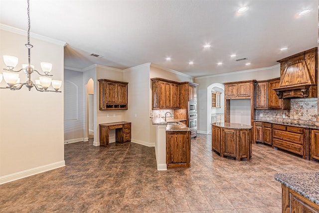 kitchen with tasteful backsplash, hanging light fixtures, ornamental molding, a kitchen island, and dark stone counters