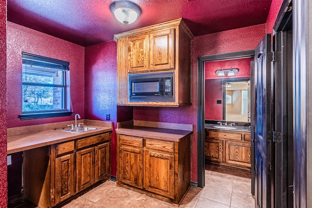 kitchen with sink, black microwave, a textured ceiling, and light tile patterned flooring