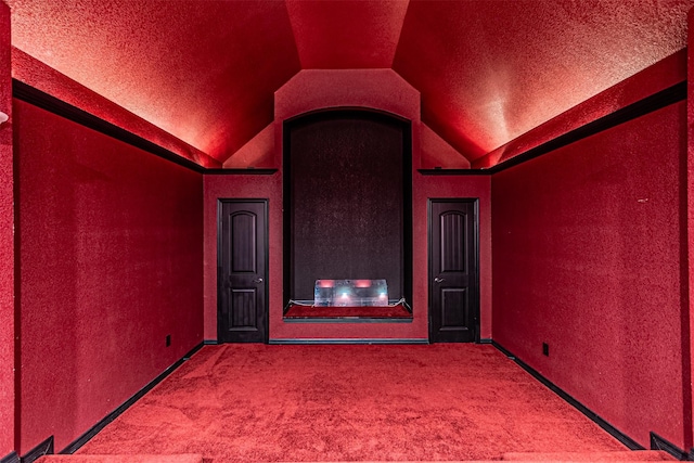 cinema room with vaulted ceiling, a textured ceiling, and carpet