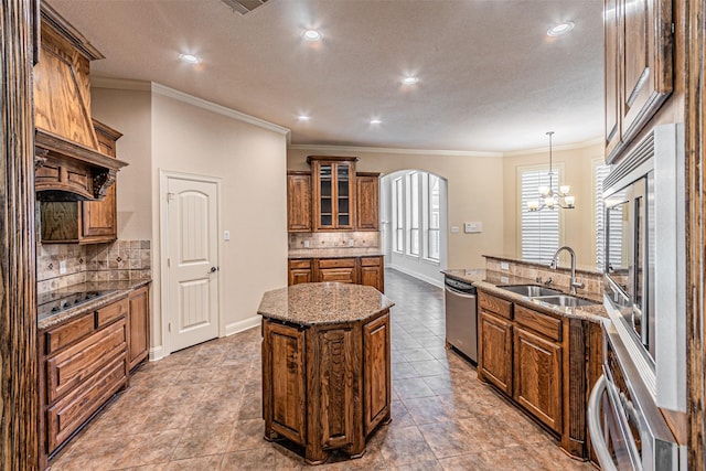 kitchen featuring sink, a center island, stainless steel dishwasher, pendant lighting, and light stone countertops