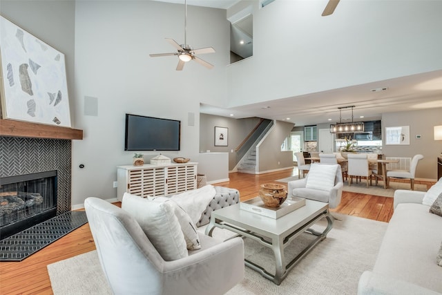 living room featuring a tiled fireplace, light hardwood / wood-style flooring, and ceiling fan