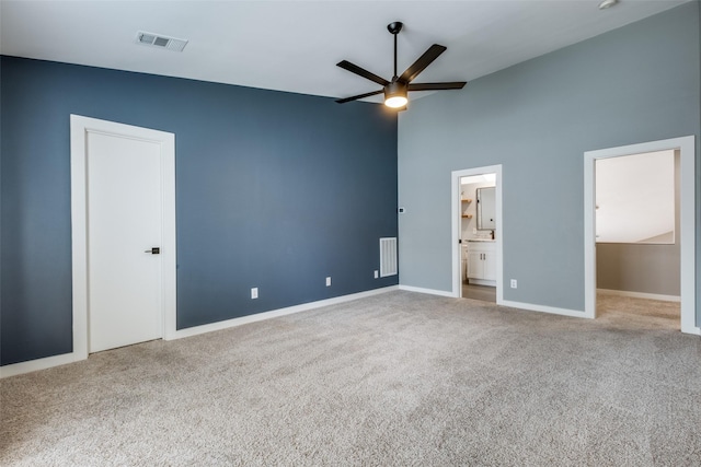 unfurnished bedroom featuring ceiling fan, a high ceiling, carpet flooring, connected bathroom, and a closet